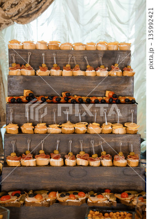 Rustic Wooden Tiered Display of Appetizers with Olives, Cheese, and Ham at Elegant Event 135992421