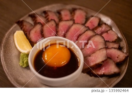 Grilled beef tongue, Gyutan, served on plate with pickled egg yolk and sauce 135992464