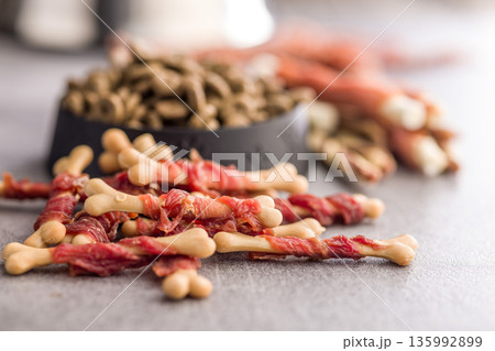 Dog food. Snack sticks for dogs and dry kibble food on gray table. 135992899