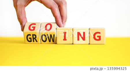 Going and growing symbol. Concept words Going Growing on beautiful wooden blocks. Beautiful white and yellow background. Businessman's hand. Business going and growing concept. Copy space. Going and growing symbol. Concept words Going Growing on beautiful wooden blocks. Beautiful white and yellow background. Businessman's hand. Business going and growing concept. Copy space. 135994325