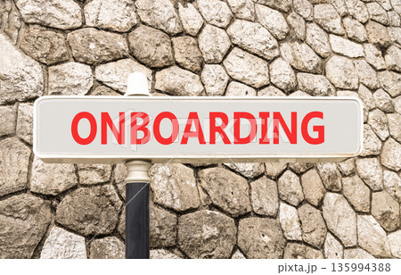 Onboarding success symbol. Concept word Onboarding on beautiful grey road sign. Beautiful stone wall background. Business onboarding success concept. Copy space. Onboarding success symbol. Concept word Onboarding on beautiful grey road sign. Beautiful stone wall background. Business onboarding success concept. Copy space. 135994388