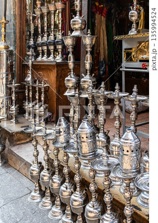 A shop in Khan El Khalili market, Cairo, is selling colourful shisha pipes. The entrance displays various ornate shisha, showcasing traditional Egyptian craftsmanship. 135994524