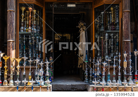 A shop in Khan El Khalili market, Cairo, is selling colourful shisha pipes. The entrance displays various ornate shisha, showcasing traditional Egyptian craftsmanship. A shop in Khan El Khalili market, Cairo, is selling colourful shisha pipes. The entrance displays various ornate shisha, showcasing traditional Egyptian craftsmanship. 135994528