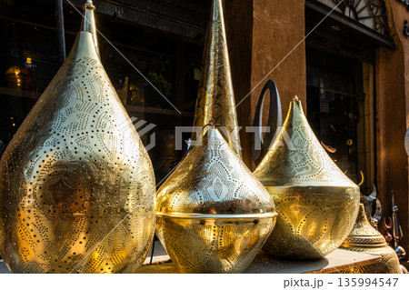 Ornate brass table lamps displayed in a market. Various shapes and sizes, reflecting traditional Egyptian craftsmanship. Ideal for Ramadan decor. Ornate brass table lamps displayed in a market. Various shapes and sizes, reflecting traditional Egyptian craftsmanship. Ideal for Ramadan decor. 135994547