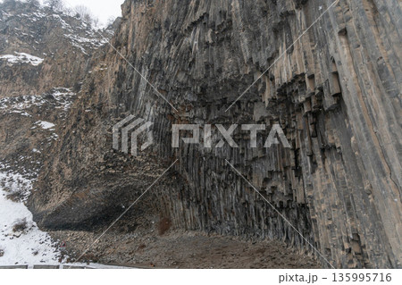 Towering vertical basalt columns form dramatic cliff wall at Symphony of Stones, layered volcanic rock creates strong geometric textures 135995716