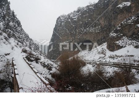 Snow-covered cliffs, winding road frame dramatic basalt formations of Symphony of Stones, winter textures emphasize the rugged canyon landscape 135995721