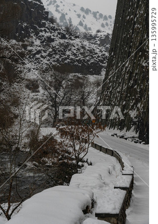 Snow-covered road and river run alongside towering basalt columns at the Symphony of Stones, dark volcanic textures contrast with winter whites 135995729