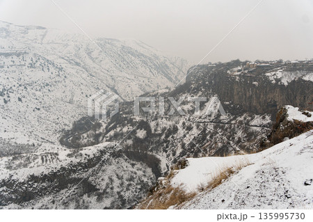 Sweeping winter panorama opens from viewpoint near Garni Temple, snow-covered cliffs and deep gorge layers fade into soft atmospheric distance Sweeping winter panorama opens from viewpoint near Garni Temple, snow-covered cliffs and deep gorge layers fade into soft atmospheric distance 135995730