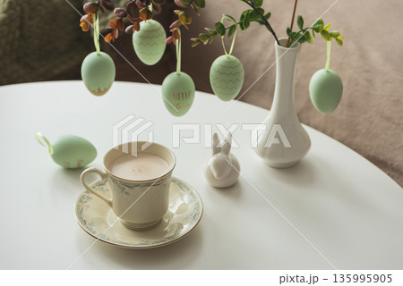 Spring Table Decor with Bunny Figurines, Hanging Eggs and Floral Cup of Coffee Spring Table Decor with Bunny Figurines, Hanging Eggs and Floral Cup of Coffee 135995905