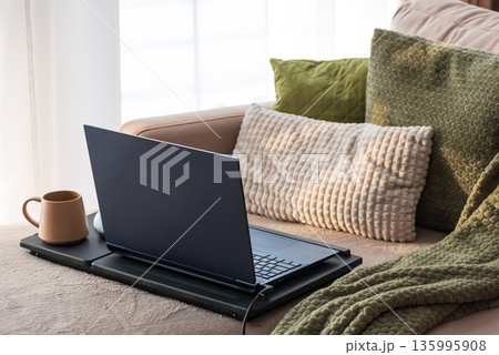 Laptop and Coffee Mug on Lap Desk. Cozy Morning Home Workspace with Green Accents 135995908