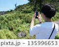 初島の風景をスマホで撮影する20代男性の後ろ姿 135996653