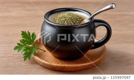 Hot drink served in black cup with herbs on top and green parsley leaf Hot drink served in black cup with herbs on top and green parsley leaf 135997097