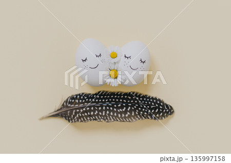 Cute Eggs with daisy flowers and feather on a yellow pastel background. Easter background. Cute Eggs with daisy flowers and feather on a yellow pastel background. Easter background. 135997158
