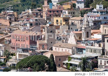 Taormina historic center with pastel houses, tiled rooftops, church bell tower and stone clock tower, Sicily Italy 135998575