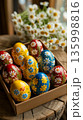 Colorful painted eggs are displayed in a box with flowers in the background during a spring celebration at a local market 135998816
