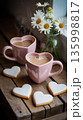 Warm coffee in heart-shaped cups with cookies and flowers on a wooden table during a cozy afternoon 135998817