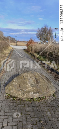 A large natural boulder lying as an obstacle or landscaping element on a roadway A large natural boulder lying as an obstacle or landscaping element on a roadway 135999873