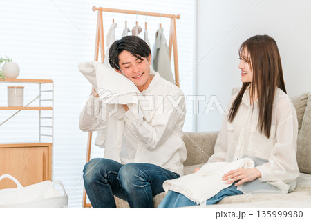 リビングで洗濯物を畳む笑顔の夫婦,カップル 135999980