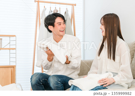 リビングで洗濯物を畳む笑顔の夫婦,カップル リビングで洗濯物を畳む笑顔の夫婦,カップル 135999982