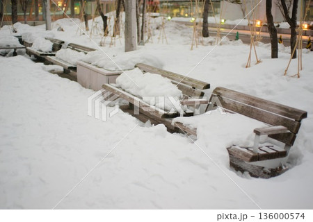 雪に埋もれた公園ベンチと冬の都市風景 136000574