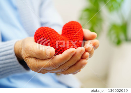 Asian elder senior woman patient holding red heart in hospital. Asian elder senior woman patient holding red heart in hospital. 136002039