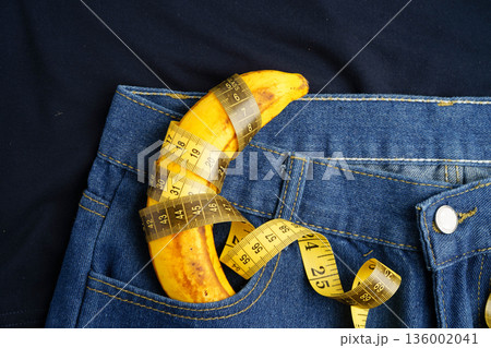 Banana with measuring tape on jean trousers, penis health. 136002041