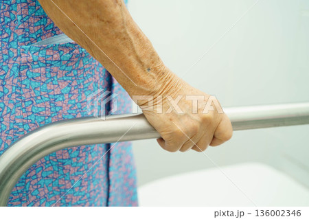 Asian elderly woman patient use toilet support rail in bathroom. Asian elderly woman patient use toilet support rail in bathroom. 136002346