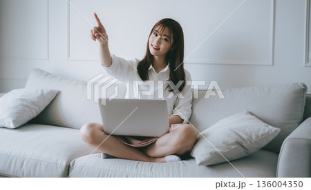 自宅でスマホを使って確定申告をする笑顔の日本人女性。指差しポーズと家計管理イメージ 136004350