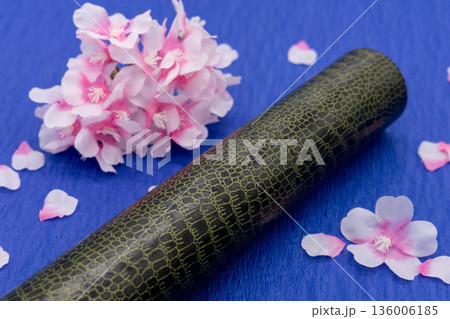 卒業証書の筒と桜の花びら 青色背景 136006185