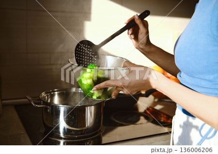 A person shifts steamed broccoli from a pot to a glass bowl A person shifts steamed broccoli from a pot to a glass bowl 136006206