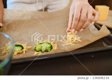 Preparation of smashed broccoli with cheese on a baking sheet in the kitchen 136006216