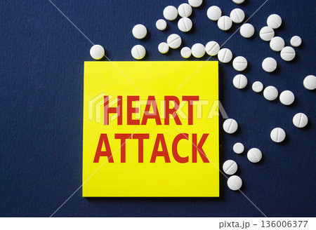 Heart Attack symbol. Concept word Heart Attack on yellow note. Beautiful deep blue background with pills. Medicine and Heart Attack concept. Copy space Heart Attack symbol. Concept word Heart Attack on yellow note. Beautiful deep blue background with pills. Medicine and Heart Attack concept. Copy space 136006377