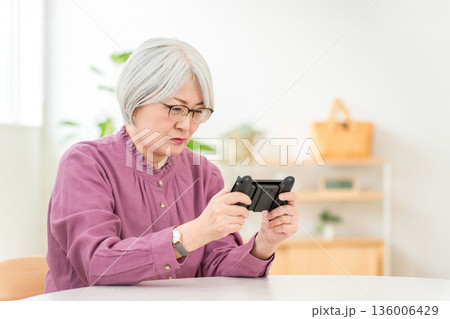家のリビングでゲームをするグレイヘアのアジア人女性 家のリビングでゲームをするグレイヘアのアジア人女性 136006429