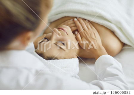 Female masseur making shoulders and neck relaxing massage to a young girl in beauty salon. Female masseur making shoulders and neck relaxing massage to a young girl in beauty salon. 136006882