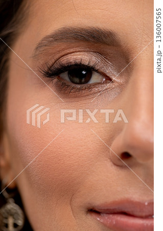 Closeup of radiant beauty, Beauty influencer with glittering cheek and subtle smile, Female model displaying luminous makeup with scattered sparkles and delicate earrings 136007565