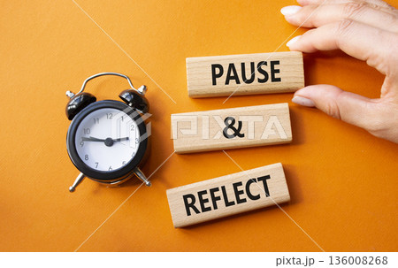 Pause and Reflect symbol. Concept words Pause and Reflect on wooden blocks. Businessman hand. Beautiful orange background with alarm clock. Business and Pause and Reflect concept. Copy space. Pause and Reflect symbol. Concept words Pause and Reflect on wooden blocks. Businessman hand. Beautiful orange background with alarm clock. Business and Pause and Reflect concept. Copy space. 136008268