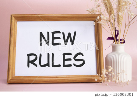 New rules symbol. Concept words New rules on beautiful wooden picture frame. Beautiful pink background with flower vase. Business and New rules concept. Copy space. New rules symbol. Concept words New rules on beautiful wooden picture frame. Beautiful pink background with flower vase. Business and New rules concept. Copy space. 136008301