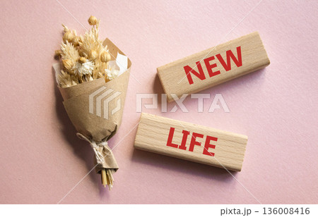 New life symbol. Concept word New life on wooden blocks. Beautiful pink background with bouquet of flowers. Business and New life concept. Copy space New life symbol. Concept word New life on wooden blocks. Beautiful pink background with bouquet of flowers. Business and New life concept. Copy space 136008416