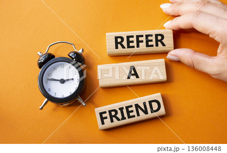 Refer a Friend symbol. Concept words Refer a Friend on wooden blocks. Businessman hand. Beautiful orange background with alarm clock. Business and Refer a Friend concept. Copy space. Refer a Friend symbol. Concept words Refer a Friend on wooden blocks. Businessman hand. Beautiful orange background with alarm clock. Business and Refer a Friend concept. Copy space. 136008448