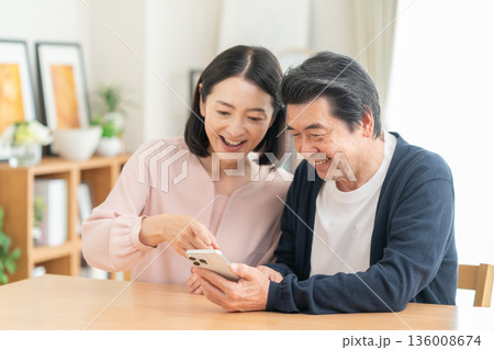 リビングでスマホを見るミドルの夫婦 リビングでスマホを見るミドルの夫婦 136008674