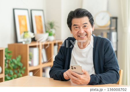 リビングでスマホを見るミドルの男性 136008702