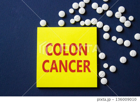 Colon Cancer symbol. Concept word Colon Cancer on yellow note. Beautiful deep blue background with pills. Medicine and Colon Cancer concept. Copy space 136009010