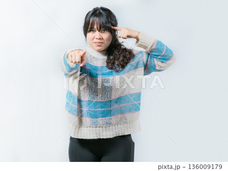 Annoyed bossy woman twirling finger to temple pointing finger at camera 136009179