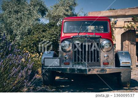Vintage red off-road vehicle parked near rustic building 136009537