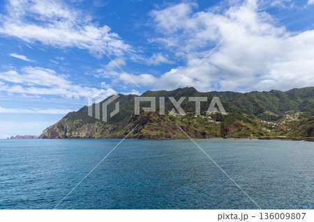 Madeira coastline near Porto da Cruz with steep mountains above Atlantic bay and village houses Madeira coastline near Porto da Cruz with steep mountains above Atlantic bay and village houses 136009807