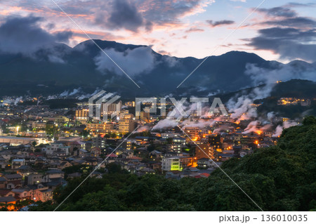 Beppu town in valley with hot spring smoke bath houses at dusk 136010035