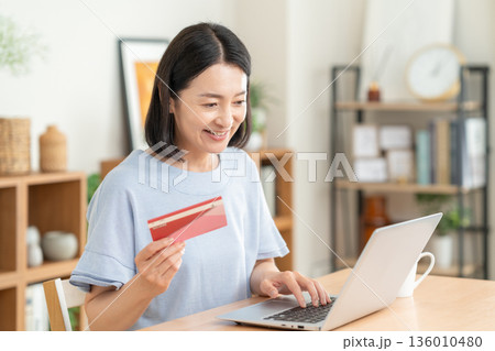 リビングで貯金通帳を見るミドルの女性 136010480