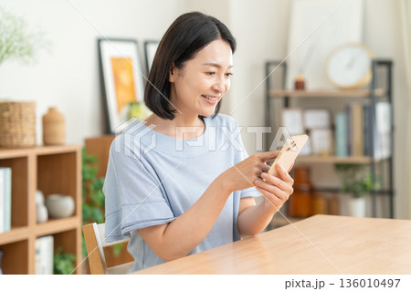 リビングでスマホを見るミドルの女性 リビングでスマホを見るミドルの女性 136010497