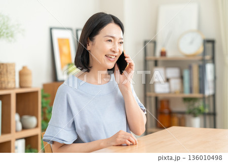 リビングでスマホを見るミドルの女性 リビングでスマホを見るミドルの女性 136010498