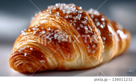 Flaky golden croissant macro with sparkling sugar crystals on a clean studio background 136011232